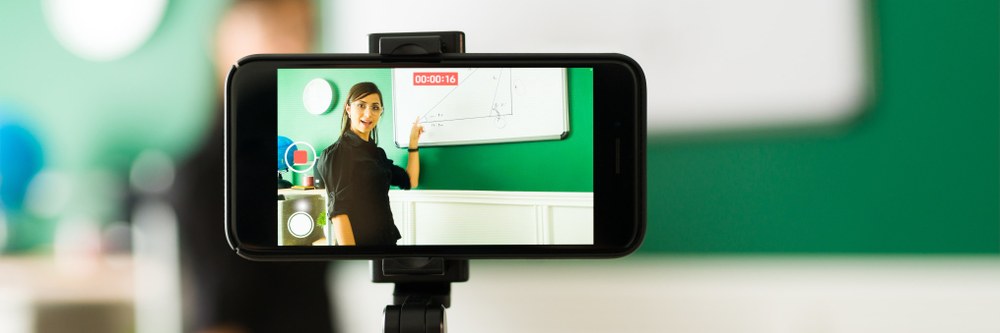 Schmuckbild Schmuckbild einer Lehrerin vor einer Tafel, die sich mit ihrem Handy selbst filmt. Quelle: tonodiaz auf Freepik
