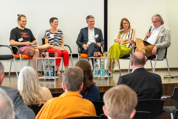 Fishbowl auf der Jubiläumstagung Fünf Personen sitzen auf Stühlen auf der Bühne.