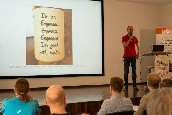 Science Slam auf der Jubiläumstagung Dr. Mathias Magdowski steht auf der Bühne und trägt seinen Vortrag vor.