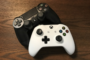 Spielekonsolen Zwei Spielekonsolen, eine Schwarze und eine Weiße, liegen nebeneinander.