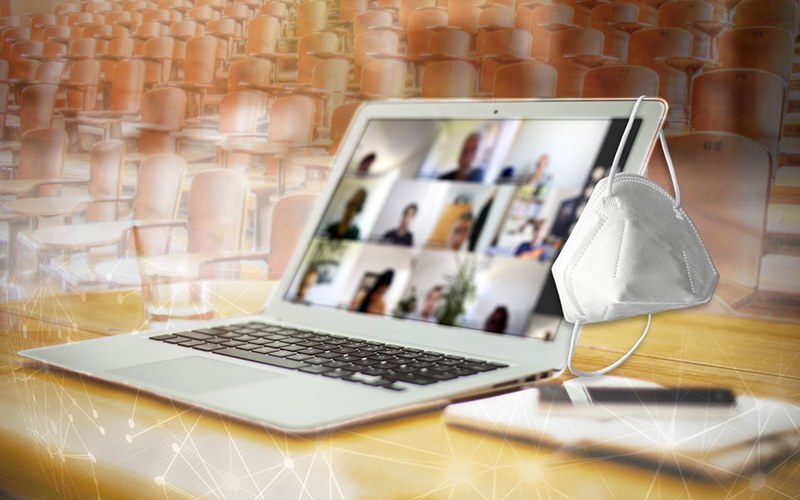 Titelbild zur Themenseite "Hochschulbildung in der Corona-Pandemie" Laptop in einem leeren Hörsaal, rechts hängt eine Maske