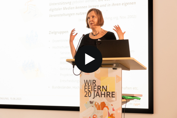 Jubiläumstagung - Neue Entwicklungen Anne Thillosen steht am Rednerpult und hält ihren Vortrag. Im Hintergrund ist ihre Präsentationsfolie zu sehen.